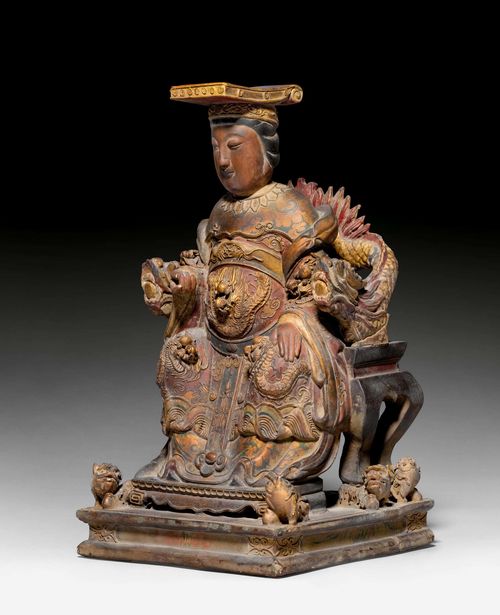 A CAMPHORWOOD CARVING OF A DAOIST FIGURE SEATED ON A DRAGON THRONE. China, 19th/20th c. Height 38 cm. Remnants of gilding, with red and green paint.