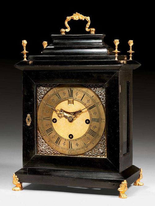 BRACKET CLOCK, George II, signed DANIEL QUARE (Daniel Quare, maitre 1708), London circa 1700. Ebonized wood case with stepped cornice and paw feet. The clock with bronze dial with "fleurs de lys", 2 fine hands, a pendulum aperture and date, fine verge escapement and 4/4 striking on 2 bells. With gilt bronze mounts and applications. The movement requires servicing. 31x18x43 cm. Provenance: Swiss private collection