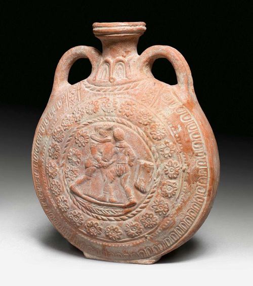 FIELD BOTTLE,Roman Imperial period, 2/3 century AD. Fired reddish clay. The sides with relief depiction of a gladiator within egg and dart and rosette border. H 24.5 cm. Provenance: - Galerie Arete, Zürich. - from a French private collection, acquired in  1973,with expertise.
