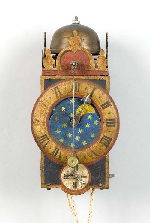 IRON CLOCK WITH MOON PHASE AND FRONT PENDULUM,Germany, 17th century. Closed, rectangular metal case with bell on top. Dial ring for the hours with piercing for the moon phase disk. Smaller dial ring for the minutes below. Clockwork mechanism and striking mechanism arranged one behind the other, striking the 1-hour on bell. H 27 cm. Painting, later. Formerly, probably with wheel balance.