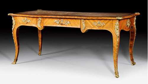 BUREAU-PLAT,Louis XV, probably by J. DUBOIS (Jacques Dubois, maitre 1742), Paris circa 1740/45. Tulipwood veneer. The shaped top lined with brown leather and edged in bronze, with a frieze in "contour à l'arbalète" and shaped legs, the front with broad central drawer, flanked by 1 drawer each side and the same but sham arrangement verso. With fine matte and polished gilt bronze mounts. 179x84.5x77 cm.