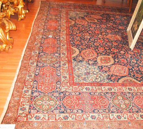 TABRIZ antique.White central medallion on a blue ground with white corner motifs, the entire carpet is opulently patterned with trailing flowers and palmettes, blue border with red cartouches, slight wear, 365x515 cm.