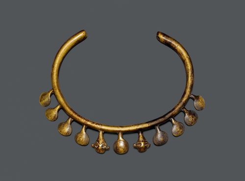 A BRONZE NECKLACE WITH 11 PENDENT ELEMENTS, NINE ENGRAVED WITH SPIRALS AND TWO WITH MINIATURE HEADS. India, Naga, antique, diameter 16.5.