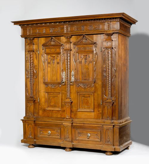 CUPBOARD,Baroque, Germany, dated 1670. Walnut, decorated with carved frieze, scrolled leaves and stylised garlands. 2 sham drawers. Architecturally structured front with double-doors. Iron lock and bands. 194x172x227 cm. Top section repaired. 1 key.