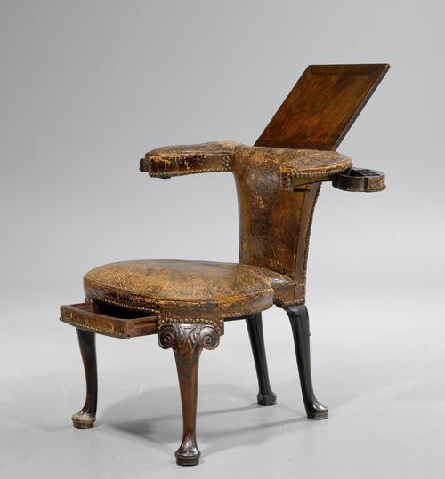 BUREAU FAUTEUIL/WRITING CHAIR,George II, England, 18th/19th century. Mahogany, finely carved with leaves and decorative frieze. Kidney-shaped seat with curved legs. Flat backrest, with foldable writing surface on stand, and padded armrests, each with 1 swing-out drawer. Defective, brown leather cover with bullen nails. Main drawer replaced. 78x60(95)x80 cm. Provenance: - from a private collection, Geneva.