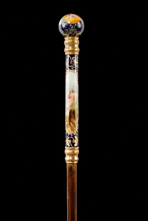 LADY'S WALKING STICK,English, 19th century. Inscribed "J. C. LEE". Porcelain sphere as a grip, connected to the shaft with a gilt collar. The wall with a figurative scene and decorated with flowers. Bamboo stick with metal tip. L 88.8 cm.