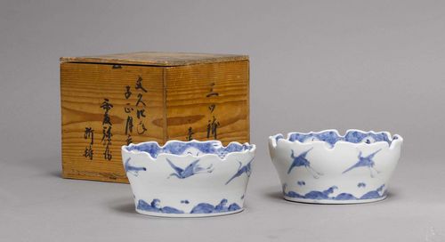 PAIR OF BLUE AND WHITE BOWLS.Japan, 19th c. D 18 cm. Arita porcelain with curved edges and cranes flying over the waves on the outer walls. Fuku mark on the bottom. Box with inscription. (2)