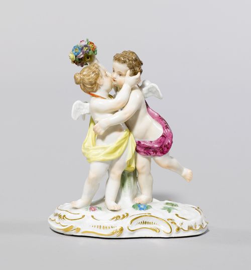 GROUP OF CUPIDS,Meissen, ca. 1900. A boy and a girl embracing, on a rocaille base accentuated in gold, and with applied flowers. Underglaze blue sword mark with pommels, model number 2986 incised, press number. H 12.5 cm.