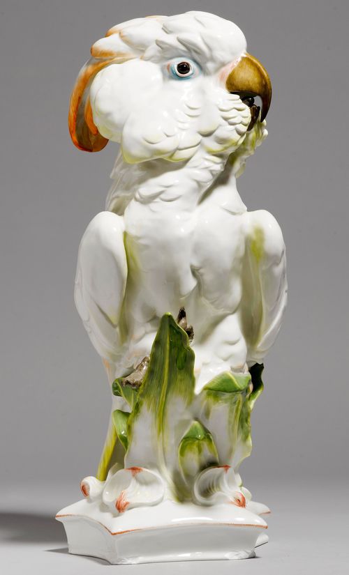 LARGE FIGURE OF A COCKATOO,Meissen, ca. 1960. Naturalistic design, the white feathers accentuated in yellow and orange, perching on a base with leaves and orchid leaves. Underglaze blue swords and jubilee mark and 1710-1960, model number q 297 incised. H 47.5 cm. Corners of the base chipped.