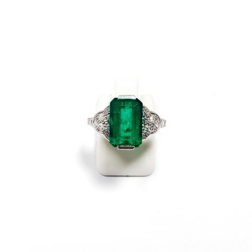 EMERALD AND DIAMOND RING, ca. 1950. Yellow gold 750 and platinum 950. Decorative ring, the top set with 1 step-cut emerald weighing ca. 3.70 ct, treated, flanked by 18 single-cut diamonds weighing ca. 0.40 ct. Size ca. 56. Oral Short Report by GGTL/Gemlab, July 2014.