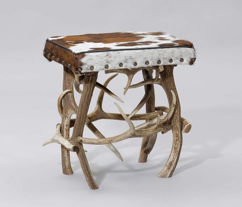 ANTLER STOOL, from theAlpine region. Rectangular, padded seat covered with a white/brown cowhide.