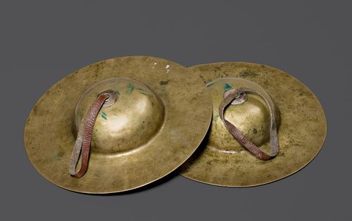 A PAIR OF CYMBALS (tib. rol-mo). Tibet, Diameter 20 cm. Metal discs with large bosses. Leather straps secured by beaded silver plates.
