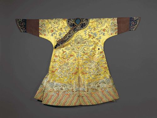 BEAUTIFUL YELLOW DRAGON ROBE with nine dragons, the twelve Imperial symbols, the Primordial Sea and Mountain of the Worlds.  Dark-yellow silk, woven decorations. Blue hems on the sleeves. With lining. China, 19th century. L 125 cm.