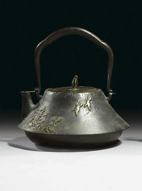 TETSUBIN with rounded floor and cone-shaped side wall. Relief decoration of a mountain temple, next to which a waterfall is depicted crashing through densely wooded cliffs. Bronze lid. Seal: Hayashi zô. Japan, early 20th century, W 20.5 cm.