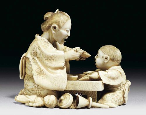 SMALL OKIMONO of ivory. A grandmother feeding her grandson. His toys are scattered around the low table, namely a doll, a lion mask, a top and a trumpet. Signed. Japan, Meiji Period, L 7.6 cm.