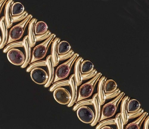 GEMSTONE AND GOLD BRACELET, BULGARI, circa 1988. Yellow gold 750, 138g. Decorated with 36 cabochons in various forms and colours: 7 amethysts, 4 citrines, 19 tourmalines and 6 ioliths totalling ca. 44.50 ct. Signed and dated L 19 cm. Width ca. 2.3 cm. Matches following lot. With case and insurance estimate.