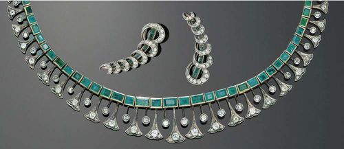 DIAMOND AND EMERALD NECKLACE AND PENDANT EARRINGS, India ca. 1900/1920. Silver and rosé gold. Very decorative necklace, the top consisting of a row of 37 emerald carrés and rectangles totaling ca.13.00 ct, signs of wear. The end pieces are formed of individual old-mine-cut diamonds mounted on fine bars interspersed with stylized floral motives, adorned with 25 old-mine-cut diamonds totaling ca. 3.30 ct. and 30 diamond roses. With a fine yellow gold anchor chain. L ca. 38.5 cm. The ear clips are each formed by a row of 7 emeralds totaling ca. 0.80 ct, surrounded by a spiral band motif with numerous diamonds, totaling ca. 1.20 ct.
