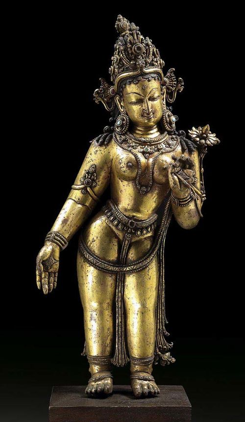 GILT COPPER ALLOY FIGURE OF STANDING GODDESS (Tara or Lakshmi) Nepal, 14th century. H 31 cm. With stone inlays. On wooden plinth.