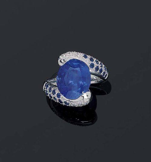 SAPPHIRE AND DIAMOND RING. White gold 750. Modern Croisé modell, top set with 1 oval Burma sapphire of 7.43 ct, not heat-treated, held together by 2 band motifs set with small sapphires and 10 brilliant-cut diamonds totalling ca 0.20 ct. Size ca 53. With Gem Report No. 112292 from the Stalwart Gem Laboratory, July 2006.