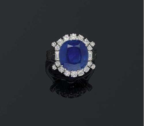 SAPPHIRE AND DIAMOND RING, ca. 1950. Platinum 950. Classic-elegant ring, the top is set with 1 antique oval Cashmere saphhire of 7.08 ct, surrounded by brilliant-cut diamonds and additionally flanked by 2 baguette-cut diamonds and 4 brilliant-cut diamonds, totalling ca.. 0.70 ct. Size 50. With SSEF Report No. 43863, November 2004.