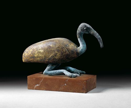 FIGURE OF AN IBIS, in antique style. Bronze and giltwood, one eye inlaid with silver. On red stone plinth. L 20 cm, H 12 cm.