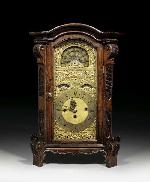 CLOCK WITH CARILLON AND ASTROLOBE, Baroque, the dial signed LORENZ HUYSEN IN BRESLAU (Lorenz Hussen, active circa 1700/40), Breslau circa 1730. Shaped and carved walnut. The case glazed on three sides. The clock with fine gilt relief-decorated bronze dial with bronze chapter ring, with two arched apertures for minutes and date and large arched aperture with moon phases and signs of the zodiac. Fine gilt and engraved brass mechanism with verge escapement and 4/4 striking on 2 bells, on the quarter hour the carillon with 10 bells, 16 hammers and 2 melodies is released. Trip repeat and regulator for the carillon. The movement requires revision. 42x24x65 cm. Provenance: Swiss private collection.