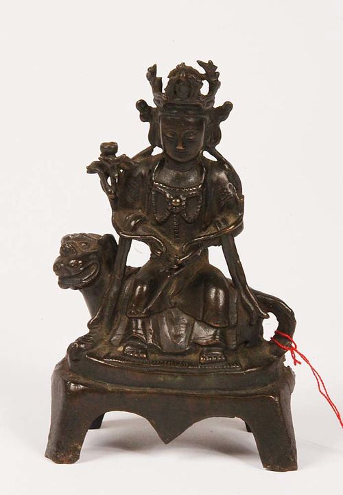 GUANYIN. Dark bronze, enthroned on a lion. With Buddha in the Boddhisattva's crown, next to the right shoulder, a lotus petal holds the begging bowl. The petal on the right is broken off, the latter part was subsequently replaced with wood. China, Ming Dynasty. H 16.5 cm.
