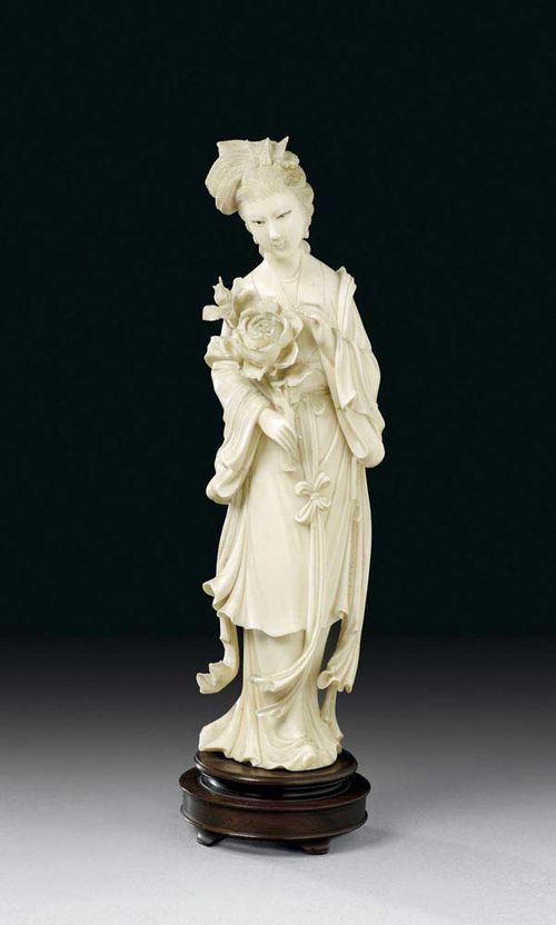 IVORY FIGURE OF A LADY. Hair in a bun with a phoenix as a decoration. She is wearing a flowing robe and holding a peony branch. China, around 1900, H with stand 28.8 cm. Slightly damaged.