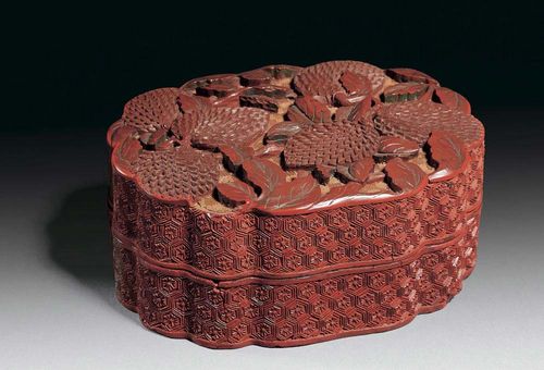 SHAPED CONTAINER WITH LID with carved decorations in red, reddish-brown and sand-colored lacquer. On the lid: six litchis between leaves on a geometric background. The sides show brocade honeycomb patterns. China, 18th century. L 12 cm. Slightly damaged.