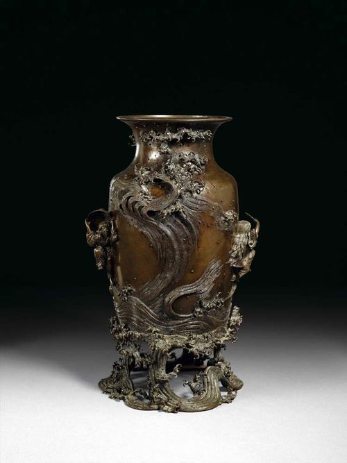 DARK BRONZE VASE. Intricate decoration in high relief. Mighty waves crowned by delicate sea foams curl around the vase up to its neck and also form the open work base. Two dancers are posed between the waves, one with a fan, the other with an inverted sake bowl over his head. Signed with a rectangular cartouche: Cast by Momose Shige (?). Meiji Period. H 41.5 cm.