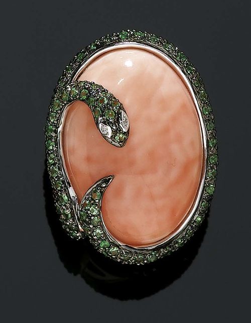 CORAL, GARNET AND DIAMOND RING. White gold 750 Attractive ring, the top set with 1 pink coral cabochon of ca. 27 x 20 mm, snake-motif mounting, set with 120 green garnets totalling ca 1.20 ct and 2 brilliant-cut diamonds totalling ca 0.01 ct. Size 56.