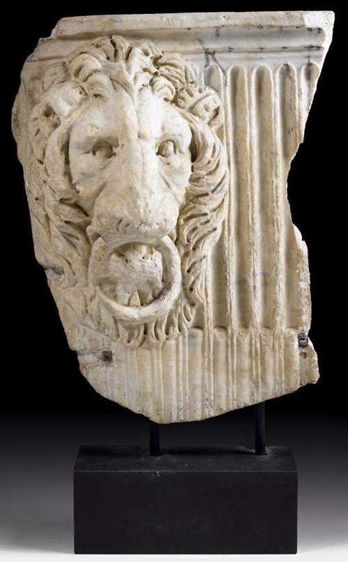 RELIEF FRAGMENT OF A SARCOPHAGUS,Roman, 3rd century AD. "Carrara" marble. Depicting a lion's head against a fluted ground. H 80 cm, W 58 cm. Provenance: from a Swiss private collection.