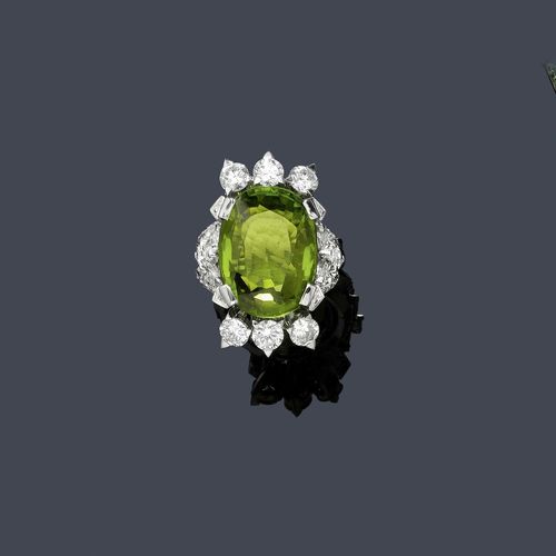PERIDOT AND DIAMOND RING, ca. 1950. White gold 750. Elegant ring, the top set with 1 very fine oval peridot of ca. 21.00 ct, within a border of 6 brilliant-cut diamonds, 6 navette-cut diamonds and 2 drop-cut diamonds weighing ca. 3.30 ct and set throughout with 56 brilliant-cut diamonds. Total diamond weight ca. 1.00 ct.