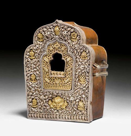 A PORTABLE BRASS SHRINE WITH SILVER FRONT SHOWING BUDDHIST SYMBOLS AND MAKARA MASK. Tibet, 19th/20th c. Height 15.5 cm. Case of felt and leather.