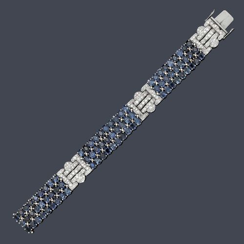 SAPPHIRE AND DIAMOND BRACELET. White gold 750, 72g. Elegant bracelet in the Art Deco style, of 3 geometrically designed ornaments set throughout with 174 brilliant-cut diamonds weighing ca. 2.60 ct and of 4 intermediate links decorated with 84 oval sapphires weighing ca. 20.00 ct and 62 brilliant-cut diamonds weighing ca. 0.50 ct. W ca. 1.6 cm, L ca. 18.5 cm.