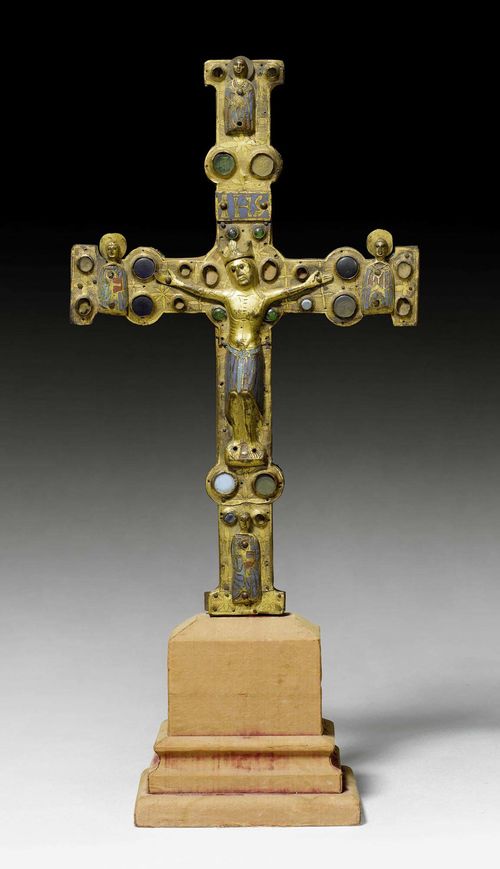 PROCESSIONAL CROSS, Limoges, early 13th century. Wooden core mounted with chased and gilt copper, set with glass stones and champlevé enamel plaques in turquoise, dark blue, red and green. The Corpus Christi in engraved, gilt and enamelled copper. One side of the cross with the crucified Christ and half-figures of the Evangelists at the cross ends. Verso with round, enamel plaque of Christ in Majesty. The cross ends with the symbols of the Evangelists. Losses and chips. Alterations. H 41 cm. Provenance: Swiss private collection. Lit.: The Metropolitan Museum of Art, Enamels of Limoges 1100-1350, New York 1996; page 315 ff.