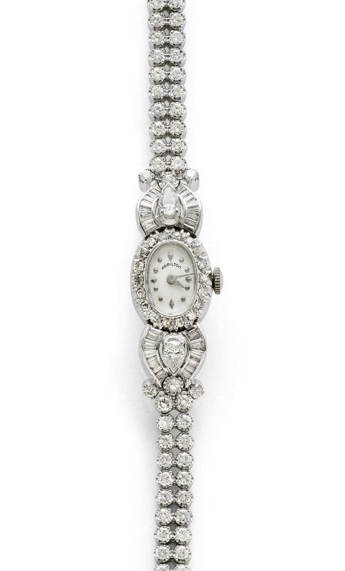 DIAMOND LADY'S WRISTWATCH, HAMILTON, ca. 1950. White gold 585. Oval case No. SD 71602, with diamond lunette weighing ca. 0.30 ct, attaches set with 2 drop-cut diamonds weighing ca. 0.80 ct, 24 baguette-cut diamonds and 6 brilliant-cut diamonds weighing ca. 1.40 ct. Textured dial with silver-coloured indices and hands, signed. hand winder, form movement signed, Cal. USA761. Double-row Rivière bracelet with 62 brilliant-cut diamonds weighing ca. 2.40 ct. L ca. 16.5 cm. D 18 x 14 mm. Matching extension element with two pairs of brilliant-cut diamonds.