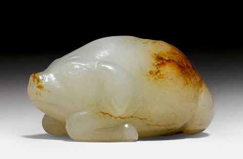A PALE CELADON AND RUSSET JADE CARVING OF A RECUMBENT PIG.