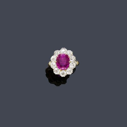 BURMA RUBY AND DIAMOND RING, ca. 1920. Yellow gold and platinum. Classic-elegant Entourage model, the top set with 1 oval fine Mogok ruby of ca. 2.90 ct and of fine colour, within a border of 10 old European cut diamonds weighing ca. 2.40 ct. Size ca. 52. Tested by Gemlab.
