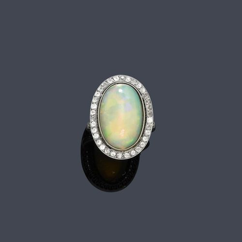 OPAL AND DIAMOND RING. Platinum. Decorative ring in the style of around 1910, the top set with 1 oval opal of ca. 6.00 ct, within a border of numerous diamonds weighing ca. 0.30 ct. Size ca. 53.