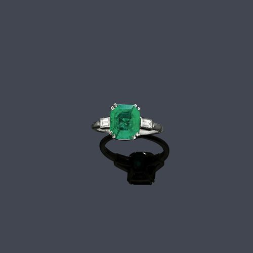 EMERALD AND DIAMOND RING, CARTIER, ca. 1950. Palladium. Classic elegant ring, the top set with 1 very fine, step-cut Columbian emerald of ca. 2.90 ct, minimal signs of wear, flanked by 2 baguette-cut diamonds weighing ca. 0.30 ct, signed Cartier No. 44 57979. Size 53.