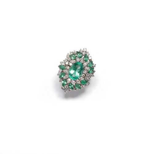 EMERALD AND DIAMOND RING. White gold 585. Elegant ring, the navette-shaped, florally designed top set with 1 oval emerald of ca. 4.00 ct, within a border of 11 navette-cut emeralds weighing ca. 2.00 ct and additionally set throughout with numerous brilliant-cut diamonds. Total diamond weight ca. 1.70 ct. Size ca. 53.