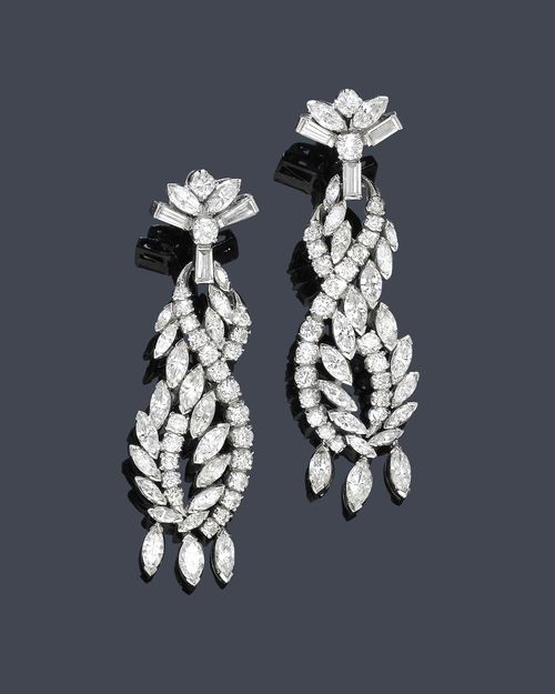 DIAMOND EAR PENDANTS, ca. 1950. Silver alloy. Classic-elegant ear studs with stylized loop motifs, the geometrically open-worked pendant set with 17 square-cut diamonds and 22 brilliant-cut diamonds each, mounted on a fan-shaped stud with 3 tapered, baguette-cut diamonds, 2 navette-cut diamonds and 2 brilliant-cut diamonds. The lower part with 3 flexibly mounted navette-cut diamonds each. Total diamond weight ca. 7.00 ct.