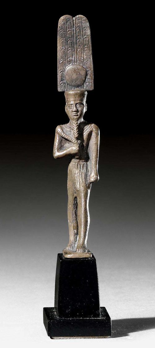 SMALL STATUETTE OF AMUN,21st -22nd Dynasty, Egypt, ca. 1000-800 BC. Silver alloy. Amon standing with a double-feather crown and Pharaoh’s beard, on a stepped base. H 8.4 cm (without base). H 11.2 cm (with base). Provenance: Austrian private collection, acquired in Vienna in the 1980s.