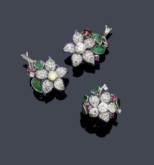 DIAMOND, RUBY AND EMERALD EAR CLIPS WITH RING. White gold 750. Fancy ear clips designed as a flower, the centre set with 1 fancy-yellow brilliant-cut diamond weighing ca. 1.00 ct, and 1 white brilliant-cut diamond weighing ca. 1.30 ct, the petals with a blue enamelled border and set throughout with numerous brilliant-cut diamonds weighing ca. 2.60 ct, the leaves set with 4 engraved emeralds and additionally set with 1 small bud set with rubies and 1 finely enamelled ladybug and 1 ruby. Matching ring with a brilliant-cut diamond weighing ca. 1.00 ct, 4 engraved emeralds, 4 rubies, and 64 brilliant-cut diamonds weighing ca. 1.50 ct in total. Size ca. 54.