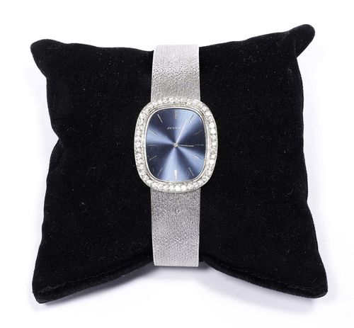 DIAMOND LADY'S WRISTWATCH, JUVENIA, 1980s. White gold 750, 57g. Oval case No. 903378 with brilliant-cut diamond lunette weighing ca. 0.80 ct. Blue dial with silver-coloured indices and hands. Manual winding, ultra-flat movement, signed. Textured Milanaise band, L ca. 18 cm. D 33 x 23 mm.