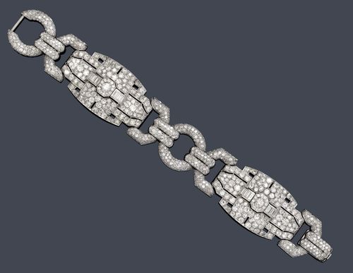 DIAMOND BRACELET, France, ca. 1930. Platinum. Fancy Art Déco bracelet of 2 geometrically designed ornaments, each with 1 central brilliant-cut diamond, older cut, weighing ca. 0.50 ct, flanked by 6 baguette-cut diamonds weighing ca. 1.20 ct and set throughout with 134 brilliant-cut diamonds and single-cut diamonds weighing ca. 10.00 ct, connected to one another by means of 2 diamond-set ring links and eyelets with a total of ca. 400 single-cut diamonds weighing ca. 3.50 ct. W 2.7 cm, L ca. 18.5 cm.