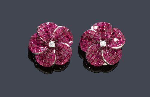 RUBY AND DIAMOND EAR CLIPS. White gold 750. Attractive florally designed ear clips with a hinged stud, the petals set throughout with numerous rubies weighing ca. 28.00 ct, invisible setting, each centre additionally decorated with 1 brilliant-cut diamond, total weight of the diamonds ca. 0.18 ct. Ca. 2.4 cm Ø.