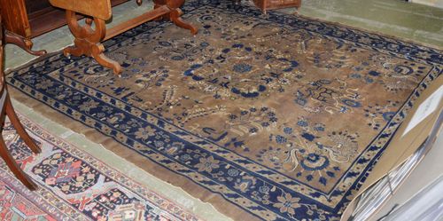 CHINESE antique. The light brown central field is patterned with floral motifs in blue and white. The dark blue border has trailing flowers. Stained, with slight wear, 245x286 cm.