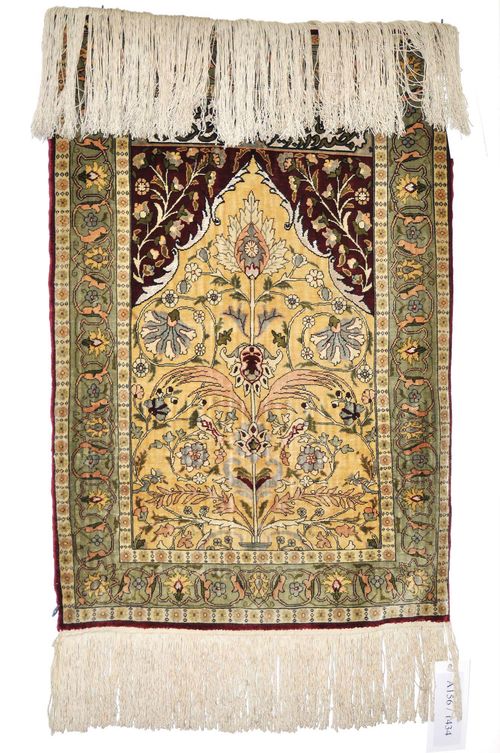 HEREKE PRAYER RUG.The beige Mihrab is decorated with a tree of life and red spandrels. With a light green border. Slightly worn, 57x80 cm.